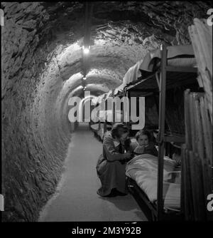 Femme agenouillée à côté d'un lit d'enfant, dans un tunnel souterrain lors du bombardement de Londres pendant la Seconde Guerre mondiale, Toni Frissell, Antoinette Frissell Bacon, Antoinette Frissell Banque D'Images