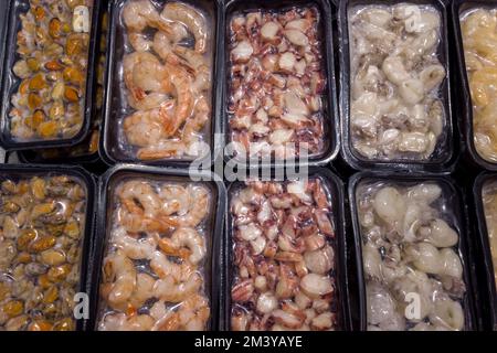 Les fruits de mer, les crevettes, les moules, les calmars et les pieuvres sont nettoyés et coupés dans des plateaux en plastique pour aliments congelés destinés à la vente au supermarché Banque D'Images