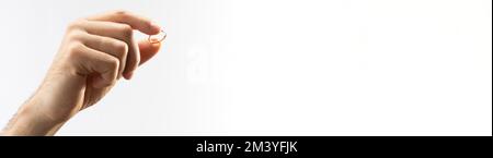 Homme tenant une bague de mariage sur un fond blanc avec un espace pour le texte. Banque D'Images