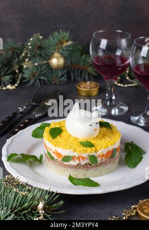 Salade de fête Mimosa pour le nouvel an avec thon en conserve, pommes de terre et carottes, lapin décoré d'oeuf, image verticale Banque D'Images