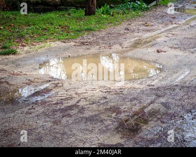 des nids-de-poule remplis d'eau sur une route sablonneuse après la pluie Banque D'Images