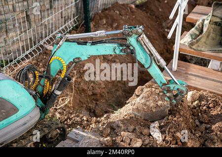 Une minipelle creuse une tranchée pour poser les tuyaux. Gros plan d'une pelle hydraulique creusant une tranchée profonde. Une pelle hydraulique creuse une tranchée dans la campagne pour déposer un Banque D'Images