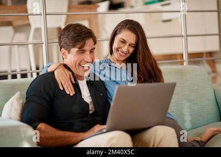 On s'est toujours amusé avec un accès Internet sans couvercle. un couple utilisant un ordinateur portable tout en se relaxant à la maison. Banque D'Images