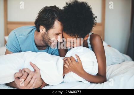 Ils n'ont pas assez d'être autour les uns des autres. un jeune couple affectueux souriant tout en partageant un moment intime dans sa chambre à la maison. Banque D'Images