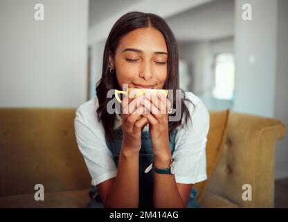 Café, femme et boisson du matin sur un salon canapé se sentant calme, détente et paix. Maison, thé et arôme naturel d'une personne qui sent et Banque D'Images
