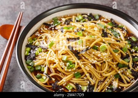 Soupe coréenne aux nouilles soba, aux algues, aux oignons verts et aux graines de sésame dans un bol sur la table. horizontale Banque D'Images