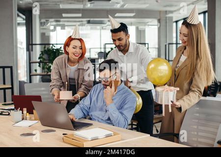 Surprise. Course mixte heureux personnes célébrant un anniversaire de collègue dans le bureau moderne Banque D'Images