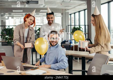 Surprise. Course mixte heureux personnes célébrant un anniversaire de collègue dans le bureau moderne Banque D'Images