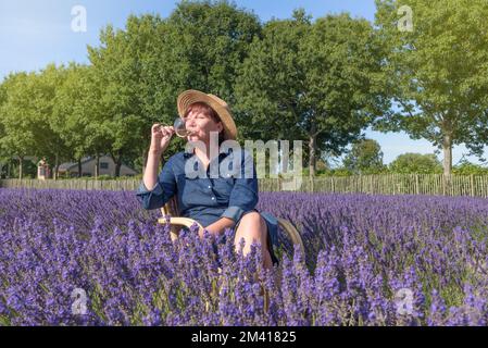 Boisson à la lavande. Femme dans le champ de lavande appréciant la liqueur de lavande Banque D'Images