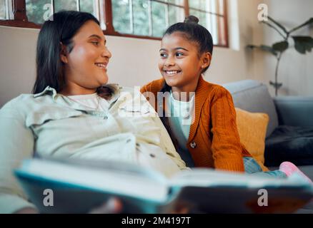 Éducation, livre et femme enceinte avec sa fille pour lire, se détendre le matin et se faire plaisir sur le canapé. Apprentissage, connaissance et mère avec un enfant pour un Banque D'Images