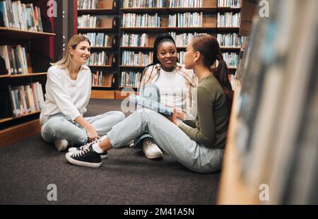 Bibliothèque, livre et groupe de femmes lisant pour l'éducation, la recherche et le savoir à l'université. Discussion, bourses et étudiantes étudiant pour Banque D'Images