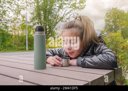 Boisson chaude lors d'une promenade automnale dans la nature. Une jeune fille qui boit dans un thermos Banque D'Images