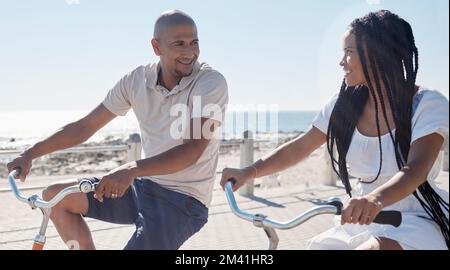 Couple, vélo et plage pour le plaisir de se lier dans une relation heureuse et aimante à Cape Town, Sea point. Cyclisme, fitness et liaison avec un homme et une femme qui font de la course Banque D'Images