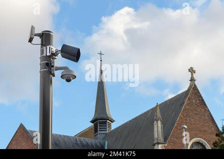 Louvain. Vlaams-Brabant - Belgique 02-01-2022. Vidéosurveillance caméra de sécurité ou surveillance opérant sur une rue de ville sur le fond d'une vieille église i Banque D'Images