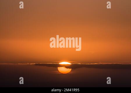 Un magnifique coucher de soleil aux couleurs orange foncé avec le soleil qui brille sous la ligne d'horizon Banque D'Images
