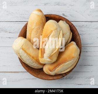Pain français, pain salé ou pistolet dans un bol sur une table en bois. Banque D'Images