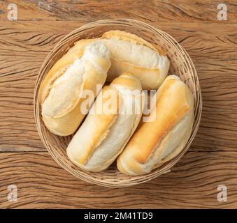 Pain français, pain salé ou pistolet dans un panier sur table en bois. Banque D'Images