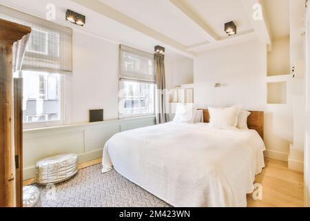 un lit dans une chambre avec parquet et draps blancs sur le cheveu Banque D'Images