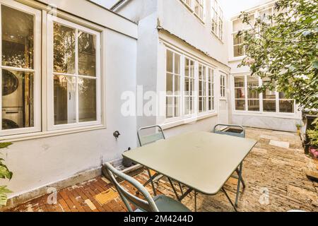 un patio avec des tables et des chaises devant une maison qui a été peinte en blanc pour correspondre à la couleur des murs Banque D'Images