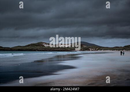 Le couple marche le long d'une côte sablonneuse à Donegal par une journée nuageux Banque D'Images