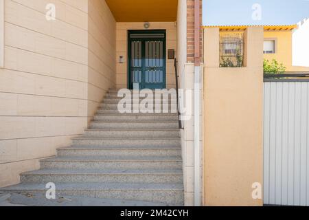 Portail d'entrée d'un immeuble résidentiel avec escaliers en granit, garde-corps en métal noir et porte d'entrée peinte en vert Banque D'Images