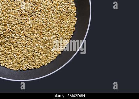 Graines de tournesol dans une casserole. Graines de tournesol grillées pelées sur fond noir. copier l'espace Banque D'Images