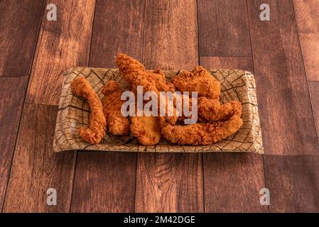 Plateau avec des doigts de poulet cuits et frits sur une table en bois Banque D'Images