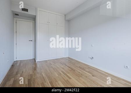 Cette chambre présente des tons bleu clair sur les murs et une armoire intégrée dotée de portes blanches avec troncs et de parquet en chêne Banque D'Images