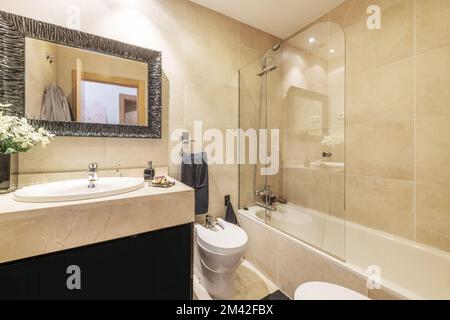 Salle de bains avec meubles en marbre crème, cabine de douche vitrée et miroir encadré de marbre Banque D'Images