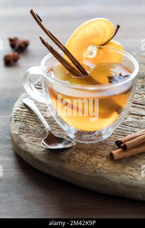 Cidre de pomme chaud fait maison dans une tasse en verre transparent, avec lumière venant de l'arrière. Banque D'Images