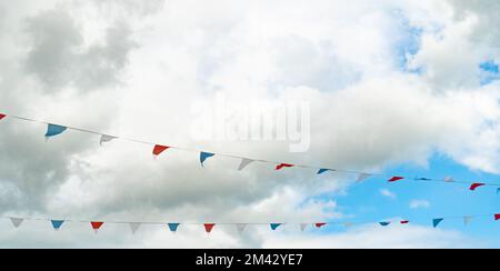 Une sélection de décorations de bunting contre le ciel bleu avec des nuages blancs Banque D'Images