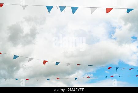 Une sélection de décorations de bunting contre le ciel bleu avec des nuages blancs Banque D'Images