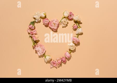 Un coeur de roses roses. Décoration florale minimaliste sur fond beige. Vue de dessus. Un agencement romantique et plat de roses parfumées délicates. Le Banque D'Images