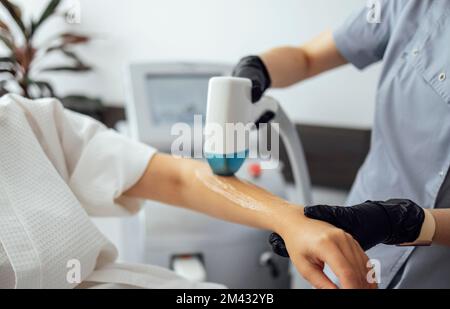 Jeune femme recevant une épilation photo lors d'une visite au centre de beauté dans un salon, esthéticienne professionnelle effectuant une procédure d'épilation au laser sur clie Banque D'Images