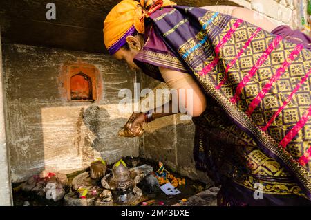 Femme locale exécutant pooja à une petite Shiva Lingam Banque D'Images