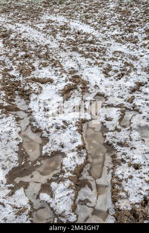 Pneus / chenilles dans un terrain boueux recouvert de gel hivernal. Pour temps froid au Royaume-Uni 2022. Banque D'Images