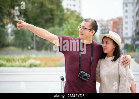 Couple multiracial de touristes explorant la ville ensemble et pointant. Banque D'Images