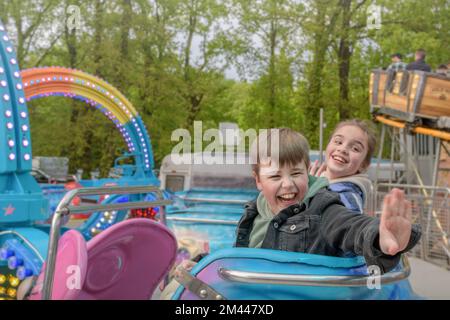 Une fille et un garçon avec une véritable émotion positive de l'expérience dans le carrousel dans le parc d'attractions. Banque D'Images