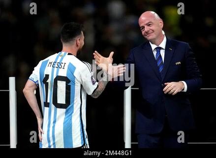 Lionel Messi, en Argentine, tremble les mains avec le président de la FIFA, Gianni Infantino, avant de recevoir le Golden ball Award après la victoire de la finale de la coupe du monde de la FIFA au stade Lusail, au Qatar. Date de la photo: Dimanche 18 décembre 2022. Banque D'Images