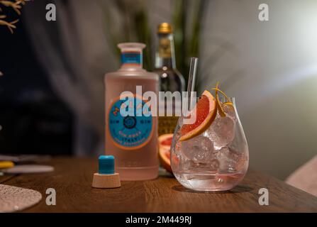 Un gros plan d'un verre de Malfy Gin Tonic au pamplemousse rose sur une table à côté des bouteilles d'alcool Banque D'Images