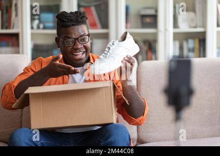 Un homme noir d'influence sur les médias sociaux examine les nouvelles chaussures Banque D'Images