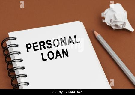 Concept commercial et financier. Sur une surface marron se trouve un stylo, du papier froissé et un bloc-notes avec l'inscription - prêt personnel Banque D'Images