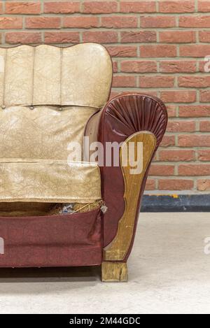 Ancien fauteuil vintage avec des traces de temps contre un mur de briques Banque D'Images