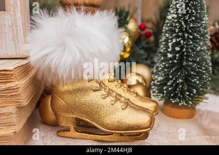 Décoration de Noël avec deux patinaines à glace. Paire de chaussures de skate dorées avec sapin. Vacances d'hiver vintage. Patins sur le dessus de la cheminée. Noël déc Banque D'Images