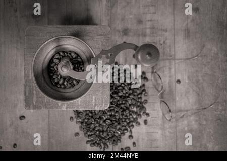 Ancien moulin à café manuel. Grains de café dispersés sur une table texturée et vieux verres pour la composition Banque D'Images