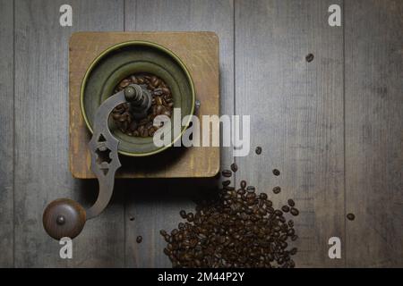 Ancien moulin à café manuel. Arrière-plan rétro avec grains de café épars Banque D'Images