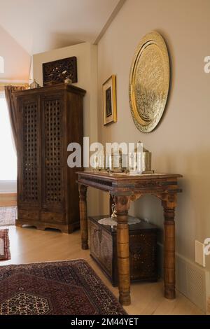 Vieille table en bois et armoire dans le style marocain décoré chambre principale avec plaque de métal décoratif doré sur le mur à l'intérieur de la maison contemporaine. Banque D'Images