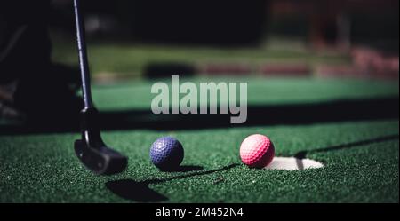 Mini-jeu de golf avec plusieurs balles de couleur dans la manière d'un putter aligné. Banque D'Images