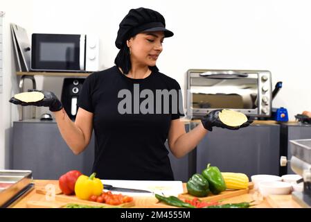 Femme mexicaine montrant des tacos pendant la cuisine Banque D'Images