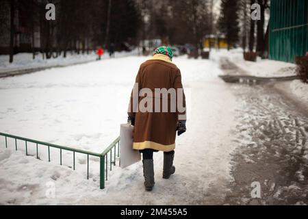 Le pensionné russe descend dans la rue en hiver. Vieille femme en Russie. Homme âgé d'Europe de l'est. Manteau à l'ancienne. Banque D'Images